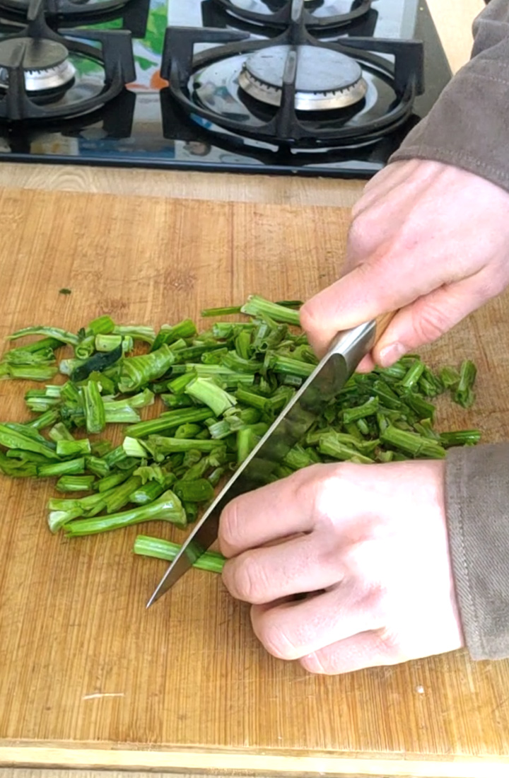 Découpe des tiges d'épinards au couteau de cuisine.